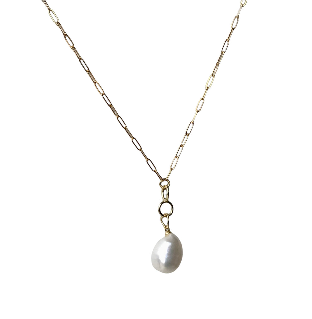 A baroque pearl pendant necklace with a gold chain. The pearl is round and white, set in a gold-plated sterling silver mounting.